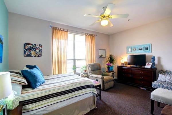 Cozy resident room with bed, chair, and TV