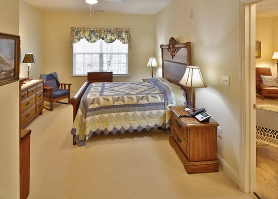 Brightly lit private resident room with a bed and furniture