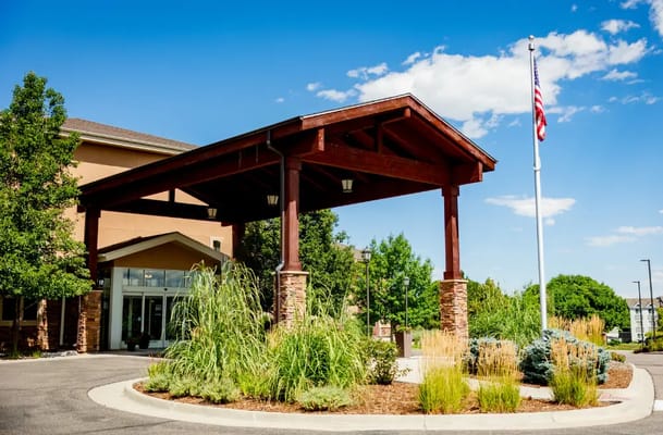 The entrance of a retirement community with a flag and landscaping