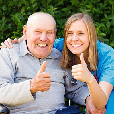 Elderly man and nurse smiling and giving thumbs up