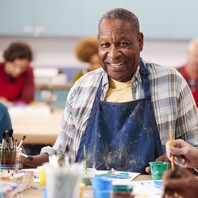 Resident enjoying a painting activity in a group setting