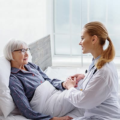 Nurse talking to an elderly patient in bed