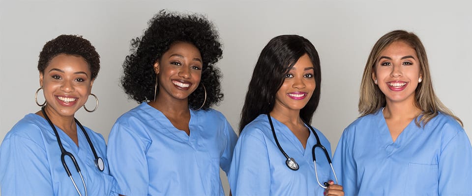 Four smiling healthcare staff members in scrubs