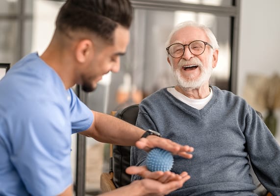 Staff engaging with a smiling resident during an activity