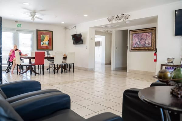 Senior woman in a wheelchair using a tablet in a common area with dining table