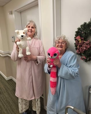 Two residents holding stuffed animals in a hallway