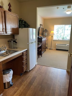 A well-lit kitchenette and living area in a senior residence.