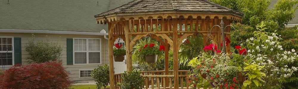 A wooden gazebo surrounded by colorful flowers