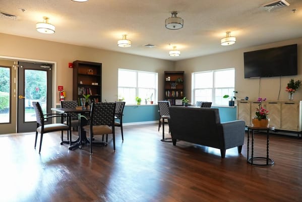 Bright common area with seating and tables for residents