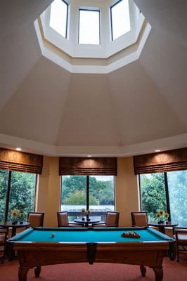 Interior view of a game room with a pool table and large windows