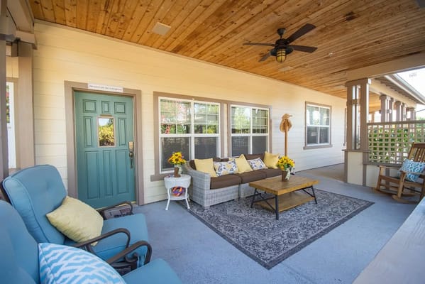Covered patio area with comfortable seating and flowers