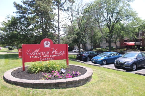 Sign for Mayfair Village Retirement Center with parking area