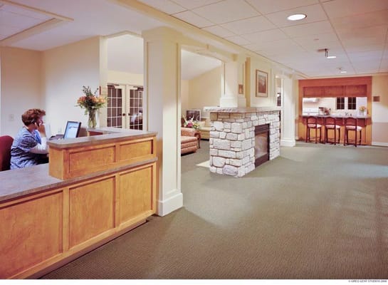 Reception area with a staff member at the desk and a cozy lounge in the background.