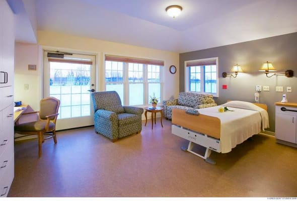 Cozy patient room with a bed, chair, and view of the outdoors.