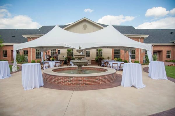 Outdoor event space with a fountain and white tablecloths