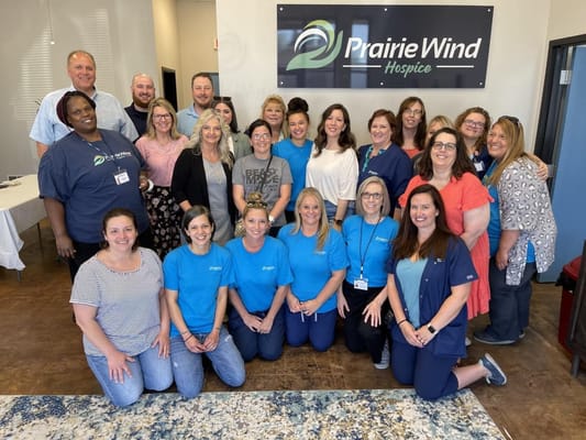Staff group photo in front of Prairie Wind Hospice logo