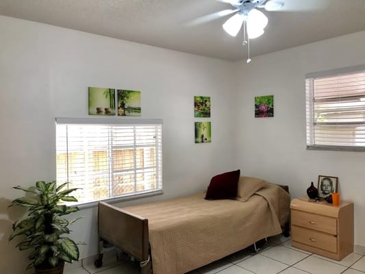 A cozy bedroom featuring a bed, bedside table, and plants.