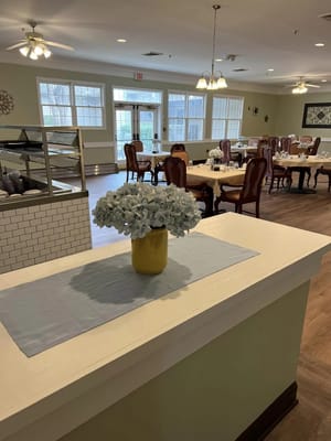 Bright dining area with tables set and a flower arrangement on a counter