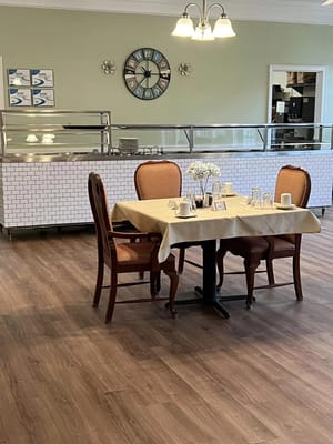 Table set for dining in a warm-toned dining room with a decorative clock.