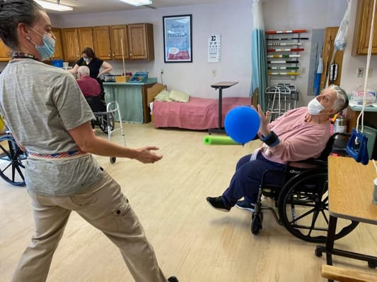 Occupational therapy session with residents using a blue balloon and green tube