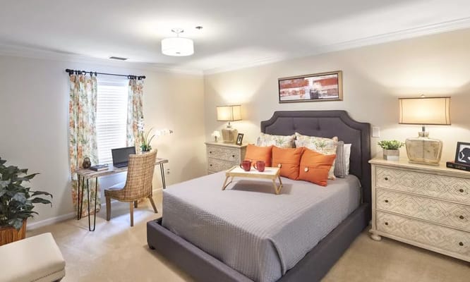 A stylishly decorated bedroom with a comfortable bed, desk, and floral curtains.