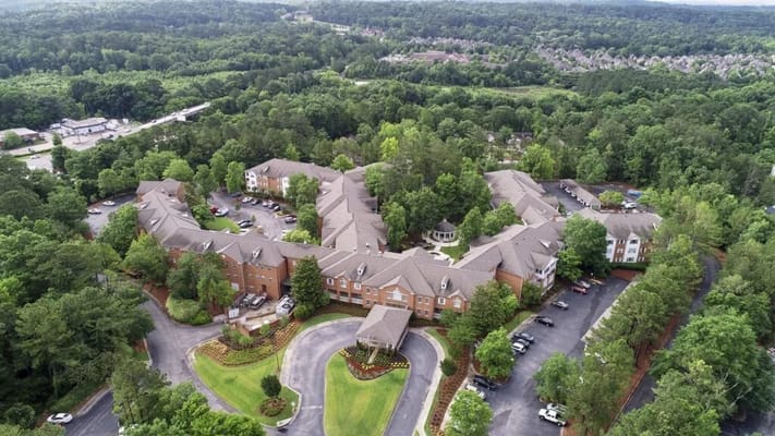 Aerial view of Galleria Woods senior living facility surrounded by green trees.