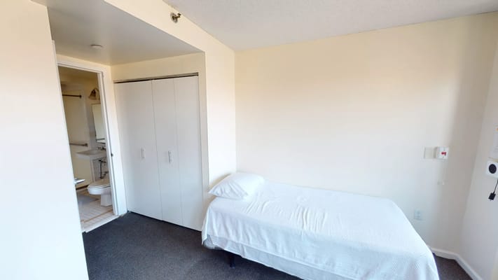 A simple private resident room with a bed and closet