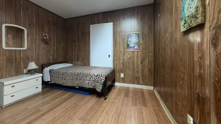 A simple resident room with wooden walls and a bed
