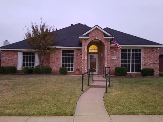 Front view of the Assisted Living Cottage with pathway and greenery.