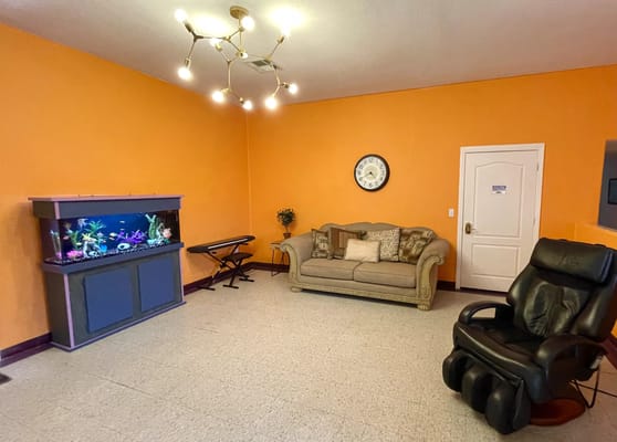 Brightly colored living room with couch, fish tank, and recliner.