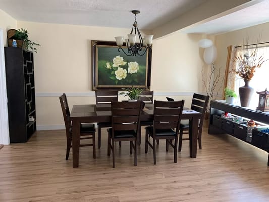 Dining table and chairs in a bright interior room with floral artwork