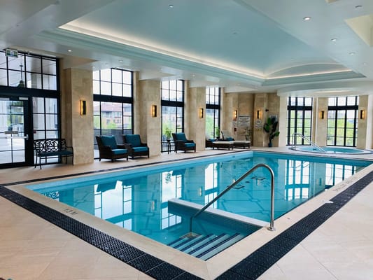 Indoor pool area with lounge chairs and large windows