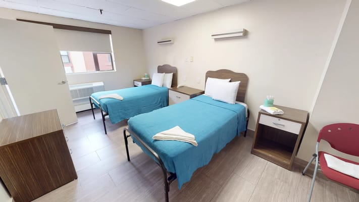 A shared resident room with two beds and bedside tables