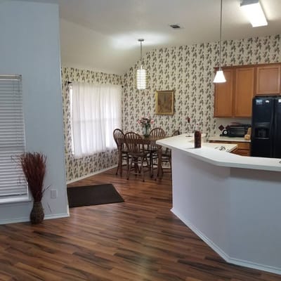 Bright kitchen and dining area with wooden floors and floral wallpaper.