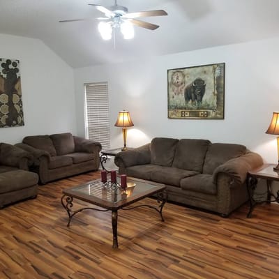 Cozy living room with brown sofas, a glass coffee table, and decorative lamps.