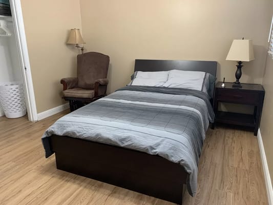Cozy bedroom featuring a bed, nightstand, and armchair.