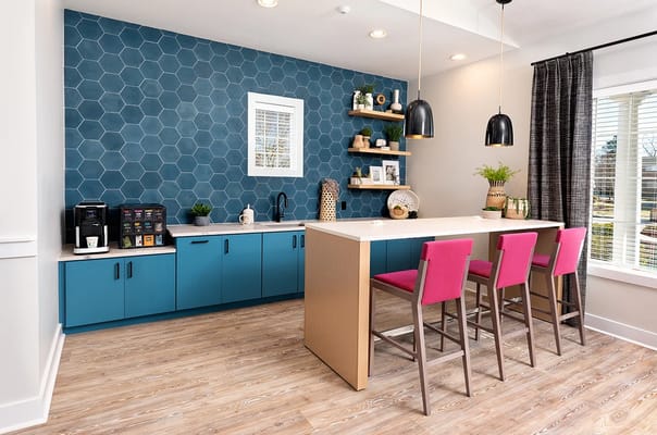 Modern kitchen area with blue cabinets and pink stools