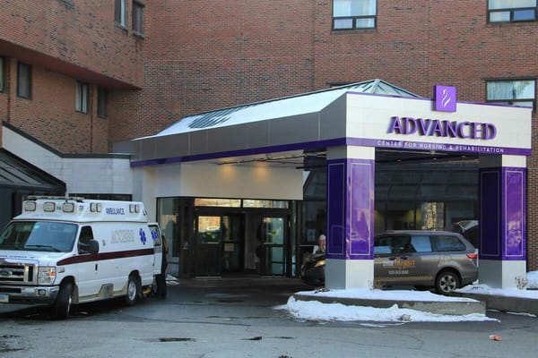 Entrance of a nursing home with ambulance and vehicles