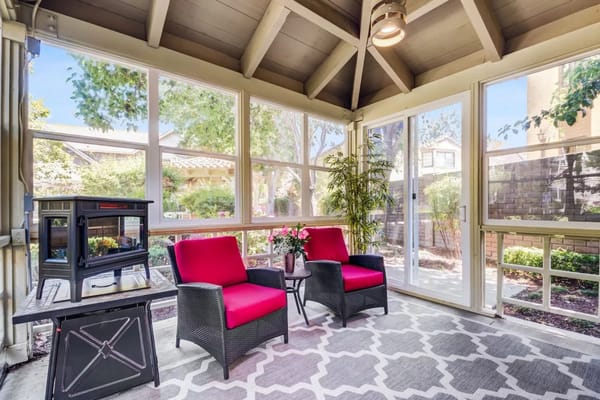 Sunroom with red chairs and plants, bright atmosphere