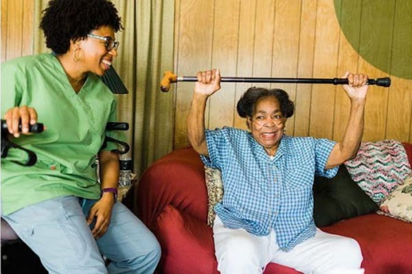 Staff assisting a resident with a cane