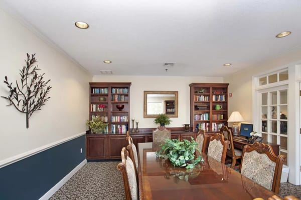 A cozy common area with wooden bookshelves and a dining table