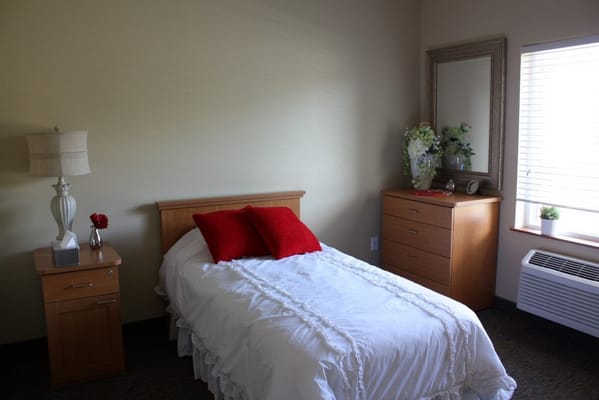A well-furnished resident room with a bed and dresser