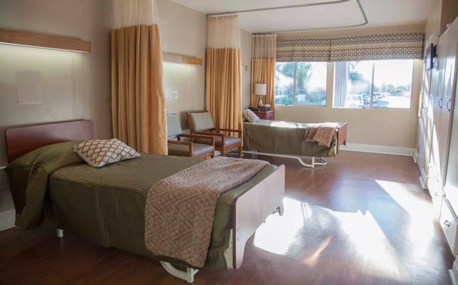 Brightly lit resident room with two beds and furniture