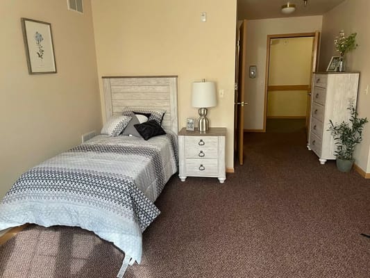 A cozy private resident room with bed and dresser