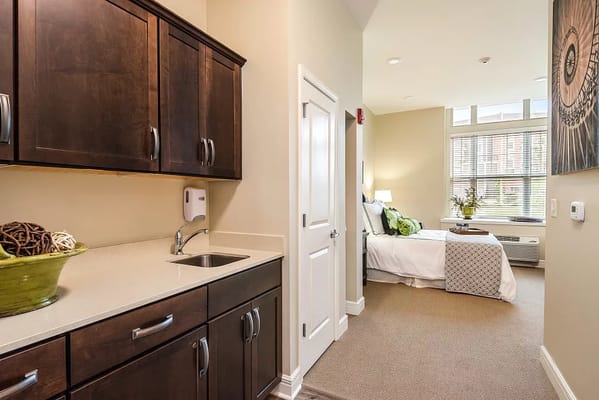 Kitchen area with a sink and cabinetry adjacent to a bedroom space.
