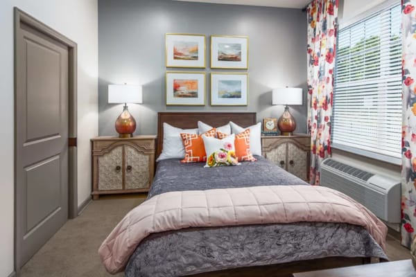 A well-decorated bedroom with a bed, side tables, and floral curtains.