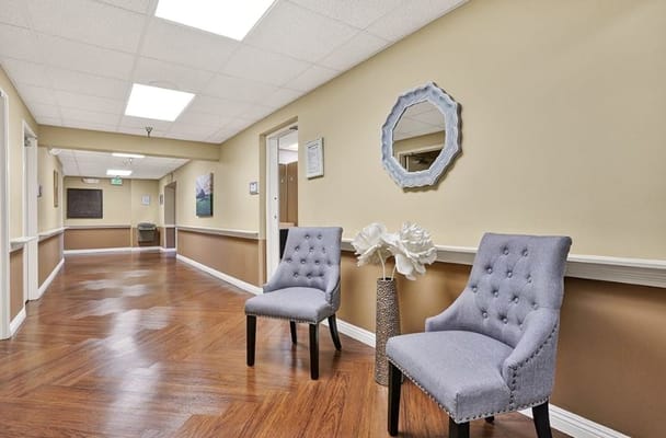 A hallway in a senior living facility with chairs and decor