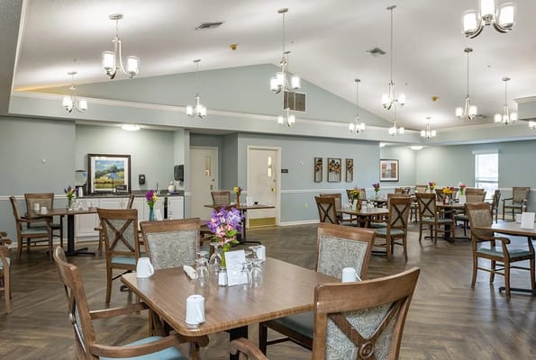 Dining room with tables set and colorful flower arrangements.