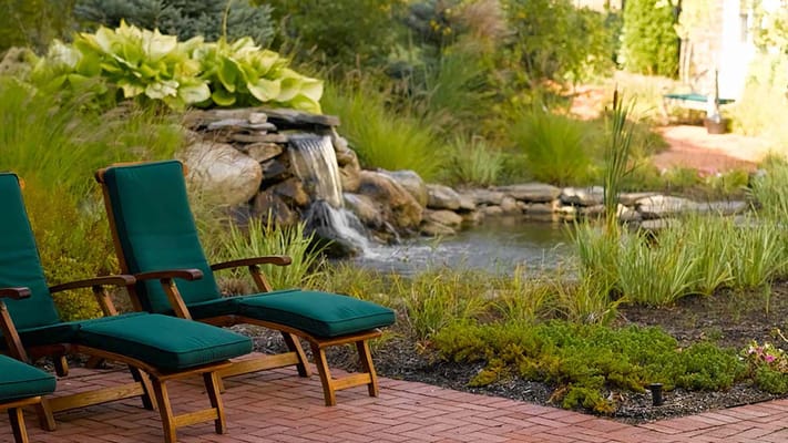 Green lounge chairs near a waterfall and garden