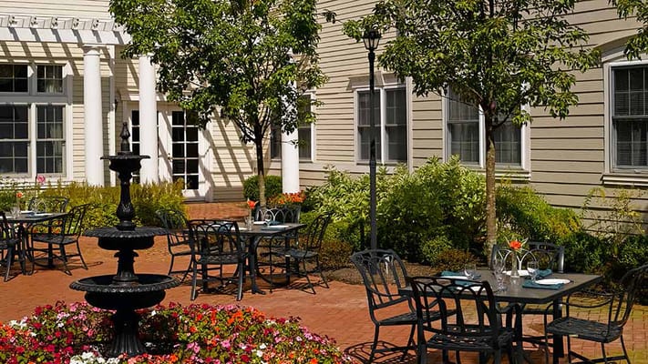 Beautiful outdoor dining area featuring a fountain and tables surrounded by flowers.